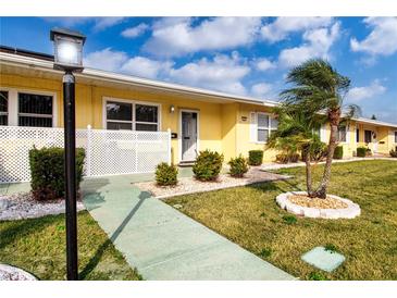 Front view of a yellow house with a walkway, landscaping, and palm trees at 1005 Rickenbacker Dr, Sun City Center, FL 33573