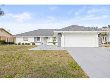 White single-story house with gray roof, two-car garage, and landscaped front yard at 2024 N Pebble Beach Blvd, Sun City Center, FL 33573