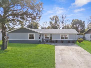 Updated home exterior featuring a gray color scheme and a well-manicured lawn at 21378 Lincoln Rd, Brooksville, FL 34601