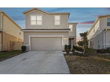 Two-story house with beige siding, two-car garage, and landscaping at 10711 Old Sycamore Loop, Land O Lakes, FL 34638