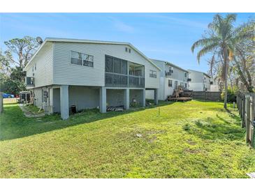 House backyard with a green lawn, wooden fence, and palm trees at 7029 Oakwood Dr, New Port Richey, FL 34652