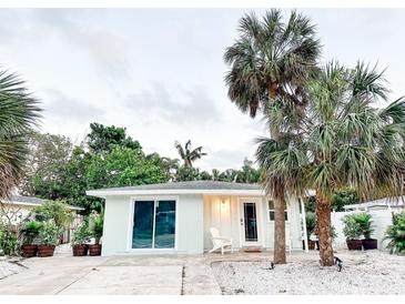 Cute bungalow with a light teal exterior, palm trees, and a white-washed front porch at 690 Fox St, Longboat Key, FL 34228