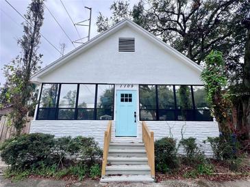 Cute bungalow with a light blue door, freshly painted white exterior, and landscaping at 1109 E 32Nd Ave, Tampa, FL 33603