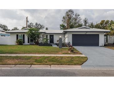 White single story home with gray garage door and landscaped lawn at 1448 S Hercules Ave, Clearwater, FL 33764