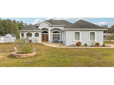 Beautiful light blue house with a large front yard and landscaping at 18520 Oak Way Dr, Hudson, FL 34667