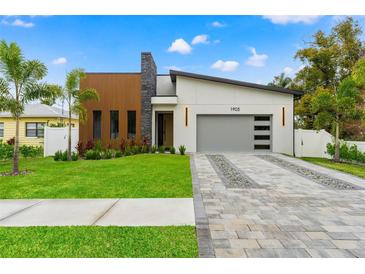 Modern home with stone and wood accents, gray garage door, and landscaped lawn at 1905 W Erna Dr, Tampa, FL 33603