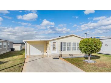 Single-wide manufactured home with attached garage and carport, featuring a well-manicured lawn at 37539 Gill Ave, Zephyrhills, FL 33541