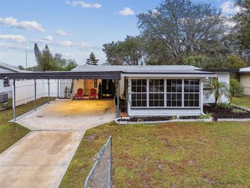 Ranch-style home with carport, landscaped yard, and spacious driveway at 7210 E Cayuga St, Tampa, FL 33610