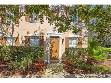 Tan house with brown shutters, lush landscaping, and a wood door at 11522 Fountainhead Dr, Tampa, FL 33626