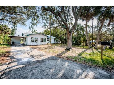 White house with blue trim, large yard at 1820 Sutherland W Dr, Palm Harbor, FL 34683