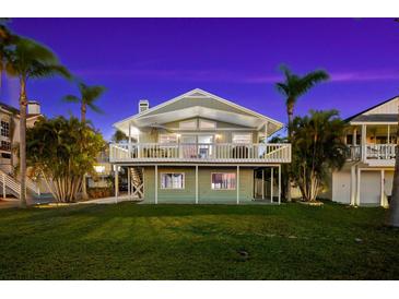 Two-story waterfront home with a large deck and lush landscaping at 555 Gulf Dr, Crystal Beach, FL 34681