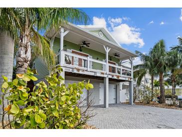 Elevated home with two-car garage, front porch, and tropical landscaping at 12116 Lagoon Ln, Treasure Island, FL 33706