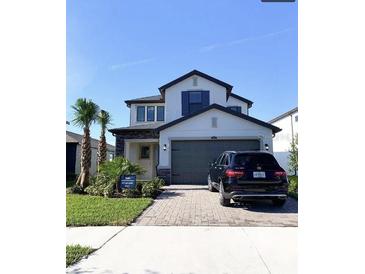 Two-story home with gray garage door and landscaping at 4861 Tramanto Ln, Wesley Chapel, FL 33543