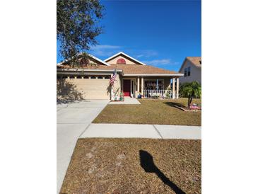 Charming single-story house with a red door, attached garage, and landscaped yard at 10808 Peppersong Dr, Riverview, FL 33578