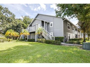 Gray condo building with exterior stairs, landscaping, and grassy yard at 11847 Skylake Pl # D, Tampa, FL 33617