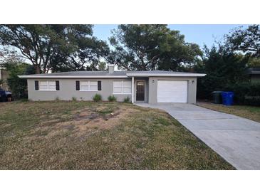 Gray house with a white garage door and a spacious lawn at 611 Pinewood Dr, Dunedin, FL 34698