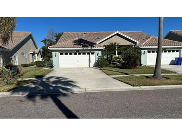 Light teal home with white garage door and landscaping at 1743 Arabian Ln, Palm Harbor, FL 34685
