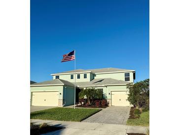 Two-story house with light green exterior, three-car garage, and a landscaped front yard at 17588 Winding Wood Ln, Punta Gorda, FL 33982