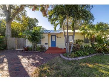 Charming yellow house with a blue door, brick driveway, and lush landscaping at 5032 19Th N St, St Petersburg, FL 33714