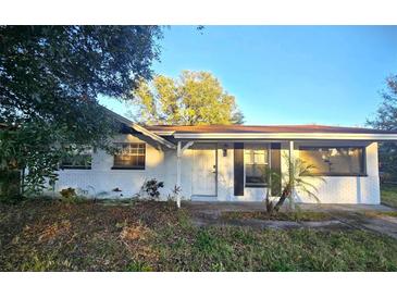 White brick ranch house with a covered porch and mature landscaping at 8533 Tidewater Trl, Tampa, FL 33619