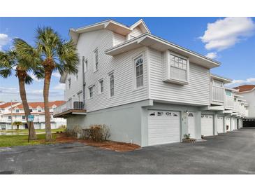 Side view of white two-story condo, showing garage and balcony at 19201 Vista Ln # C8, Indian Shores, FL 33785