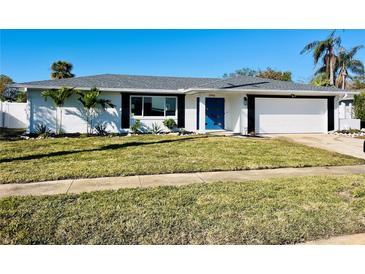 Newly renovated home with white brick exterior, gray roof, and a blue front door at 3946 Doral Dr, Tampa, FL 33634