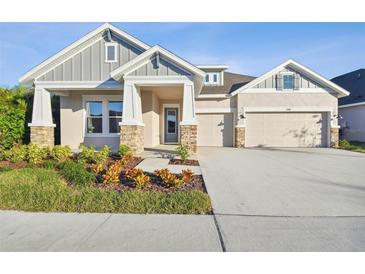 Two-story house with gray siding, stone accents, and a three-car garage at 7306 Paradiso Dr, Apollo Beach, FL 33572