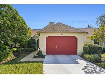 Inviting home exterior featuring a red garage door and well-manicured lawn at 8308 Antigua Ct, Port Richey, FL 34668