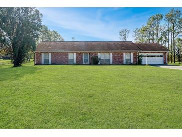 Brick ranch house with attached garage and large grassy yard at 10813 Dixon Dr, Riverview, FL 33579