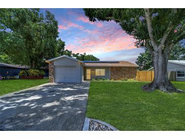 House exterior featuring a stone facade, green lawn, and driveway at 11505 Blackbark Dr, Riverview, FL 33579