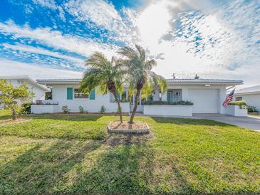 White brick ranch house with teal accents, palm trees, and American flag at 14052 89Th Ave, Seminole, FL 33776