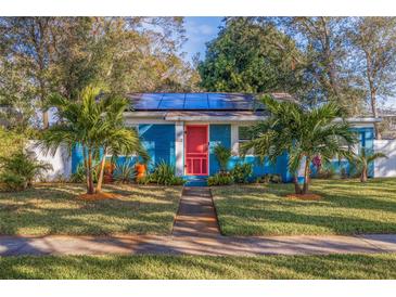 Quaint bungalow with bright blue exterior, solar panels, and lush landscaping at 5719 23Rd S Ave, Gulfport, FL 33707