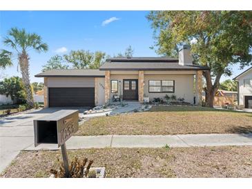 Charming one-story home featuring stone accents, a dark colored garage door, and a neatly maintained lawn at 1033 Jamaica Way, Tarpon Springs, FL 34689