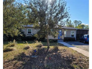 Tan one-story house with blue door, landscaping, and driveway at 1230 32Nd N St, St Petersburg, FL 33713