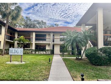 Building 13 exterior shows walkway to condo building with landscaping and palm trees at 1310 Hammock Pine Blvd, Clearwater, FL 33761