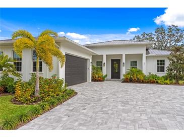 Modern home's front exterior features a gray garage door and paver driveway at 201 S Shade Ave, Sarasota, FL 34237