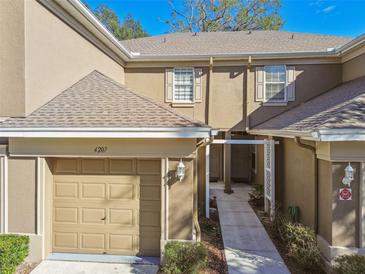 Tan two-story townhome with attached garage and walkway at 4207 Key Thatch Dr, Tampa, FL 33610
