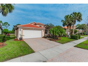 Single-story home with a white garage door, landscaping, and brick driveway at 4936 Sandy Brook Cir, Wimauma, FL 33598