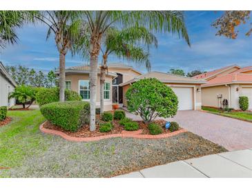 Well-maintained house with palm trees, landscaped yard, and brick driveway at 5004 Sandy Brook Cir, Wimauma, FL 33598