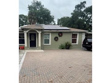 Green house with solar panels, paver driveway, and landscaping at 6207 16Th S Ave, Tampa, FL 33619