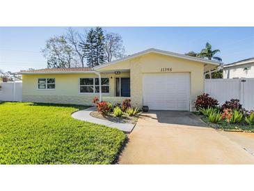 Updated yellow house with a white garage door and landscaped lawn at 11398 88Th Ave, Seminole, FL 33772