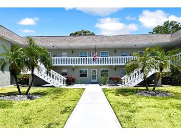 Condo building with two-story exterior, white railings, palm trees, and walkway at 1250 S Pinellas Ave # 713, Tarpon Springs, FL 34689