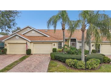 Beige exterior villa with double garage and lush landscaping at 2315 New Orchard Ct, Sun City Center, FL 33573