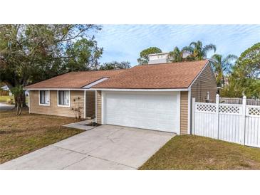 Tan house with white garage door and white privacy fence at 102 Shoreview Ln, Oldsmar, FL 34677
