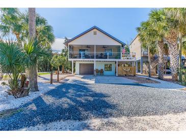 Two-story house with screened porch, gravel driveway, and tropical landscaping at 3478 Gum Dr, Weeki Wachee, FL 34607