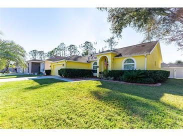 Nice yellow house with a landscaped yard and a two-car garage at 5215 New Brittany Ln, Zephyrhills, FL 33541