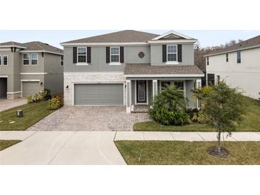 Two-story house with gray siding, gray garage door, and landscaping at 18079 Ramble On Way, Land O Lakes, FL 34638