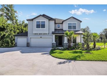Two-story house with three-car garage, stone accents and lush landscaping at 18437 Purple Creek Ln, Lutz, FL 33549