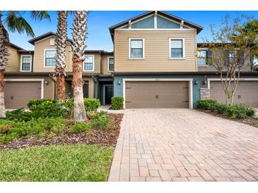 Tan two-story townhome with brown garage doors and landscaping at 28523 Pleasant Bay Loop, Wesley Chapel, FL 33543
