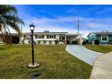 Ranch style home with carport, well-manicured lawn, and mature landscaping at 1205 Chevy Chase Dr, Sun City Center, FL 33573